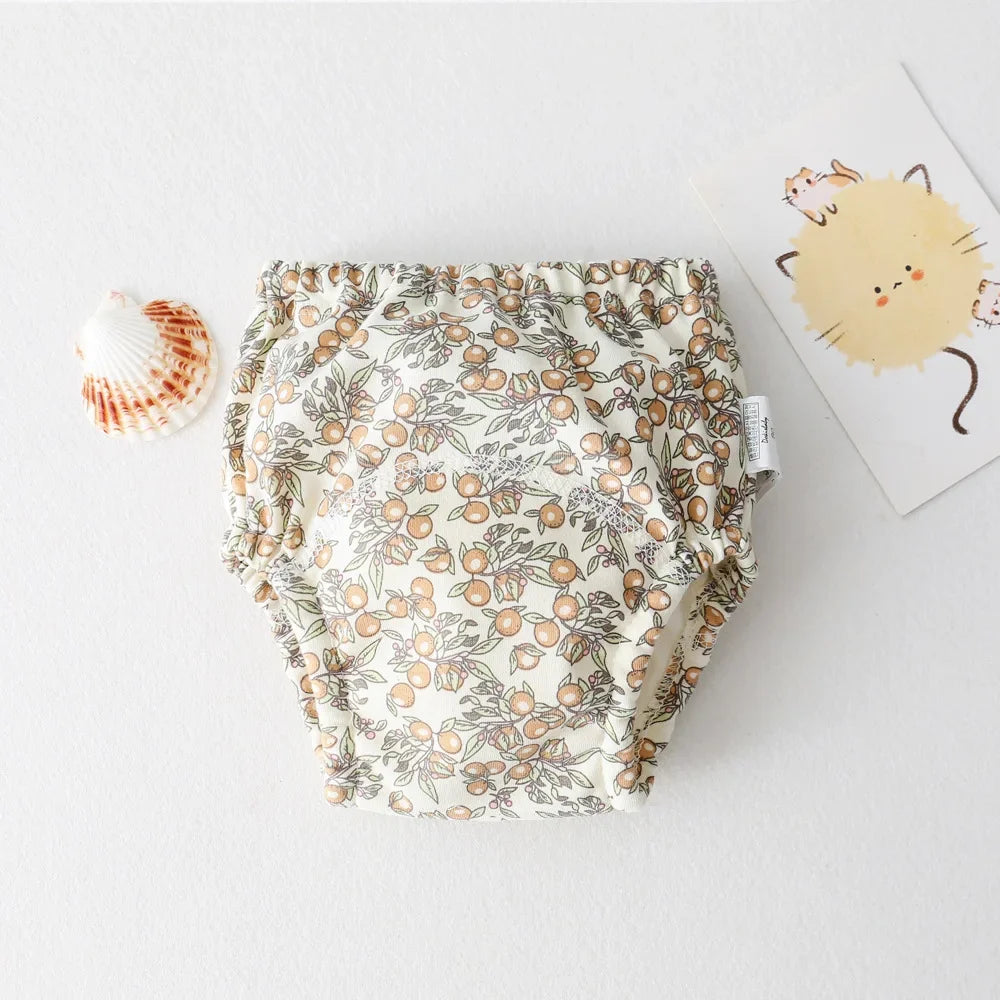 Parwani reusable baby training pants with floral pattern placed on white surface next to a seashell and cat illustration