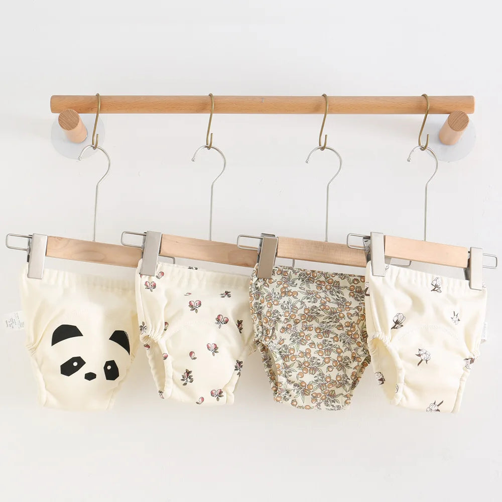 Parwani reusable baby training pants in cute animal and floral prints hanging on wooden hangers