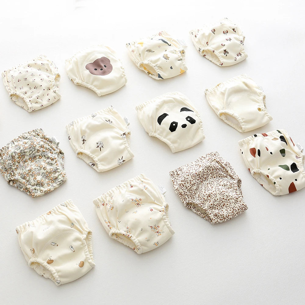 Parwani reusable baby training pants in various animal and floral prints laid out on a white surface