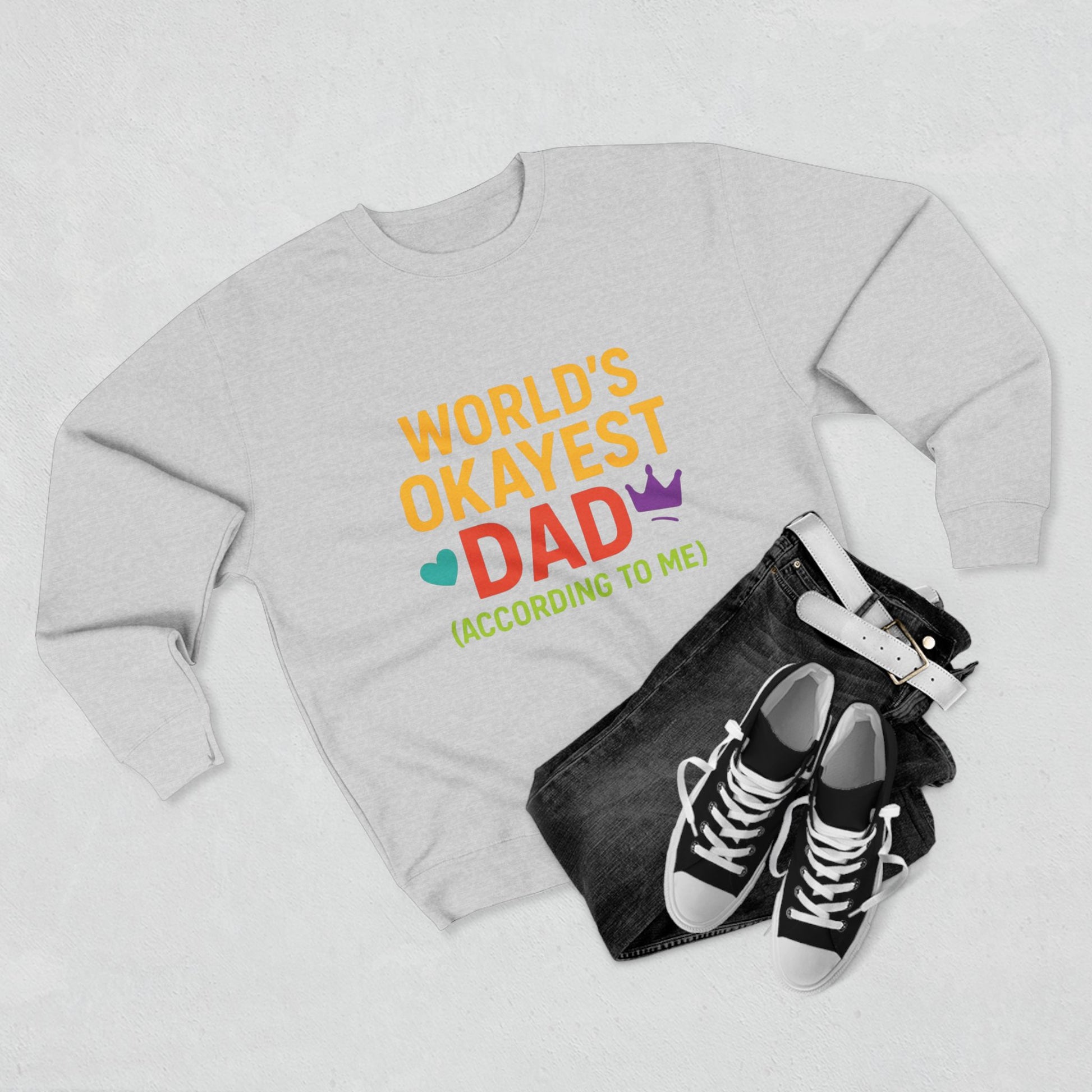 Gray sweatshirt with 'World's Okayest Dad' text, black jeans, and black sneakers on a light gray background